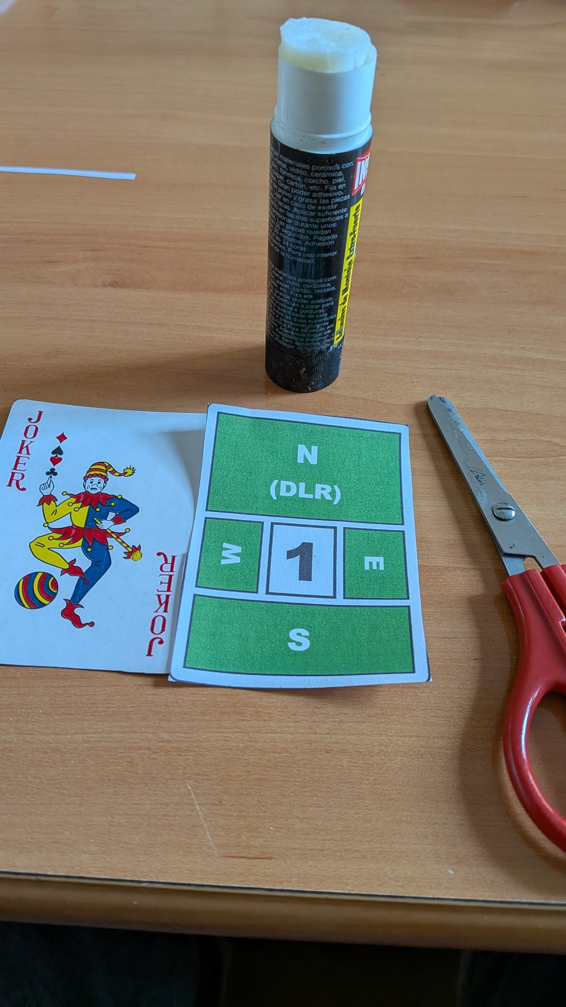 Board identifier card next to a joker playing card and scissors
